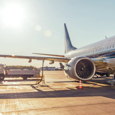InnoFuels Projektbild Ein Passagierflugzeug auf einem Flughafen, das bei hellem Sonnenlicht und blauem Himmel von einem Tankwagen betankt wird.