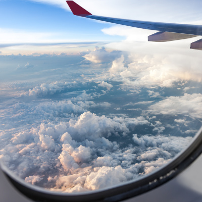 CENA SAF-Outlook Aufnahme aus einem Flugzeugfenster mit Blick auf einen Flugzeugflügel und auf den blauen Himmel mit Wolken.
