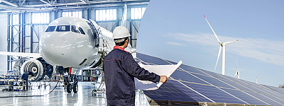 Header I Projekte I Projects Zwei Bilder werden durch einen geschwungenen Bogen, dem CENA-Bogen, voneinander optisch getrennt. Auf dem linken Bild befindet sich ein Flugzeug in einer Hallte. Auf dem rechten Bild sind Solaranlagen und Windkraftanalgen abgebildet. Ein Mann mit einem Schutzhelm und einem großen Plan in der Hand steht mittig der beiden Bilder.