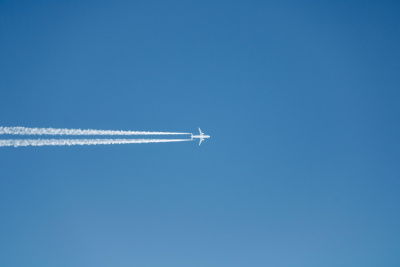 Kondensstreifen am Himmel Ein Verkehrsflugzeug fliegt am blauen Himmel und hinterlässt zwei lange, weiße Kondensstreifen.